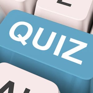 A close-up of a computer keyboard with a large blue key labeled QUIZ in white letters, inviting users to test their dental knowledge, surrounded by other white keys.